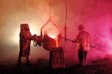 Pouring molten iron in a steel mill reenactment, metallurgical workers with ladle bucket, hot, smoky, and dangerous, Bethlehem, Pennsylvania, USA.