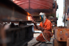 Welder welding girder in shipyard workshop